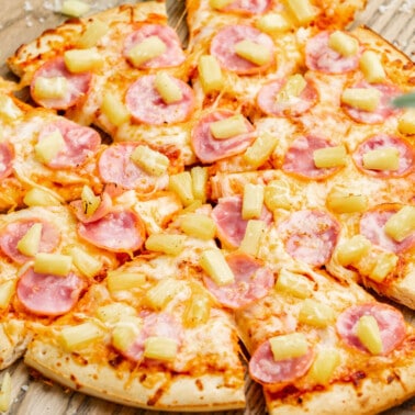 Hawaiian pizza on a wood table.