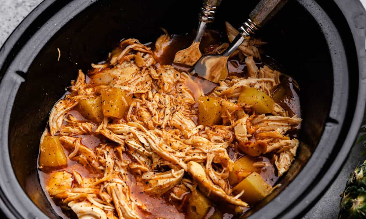 A close up view into a slow cooker full of Hawaiian BBQ chicken.
